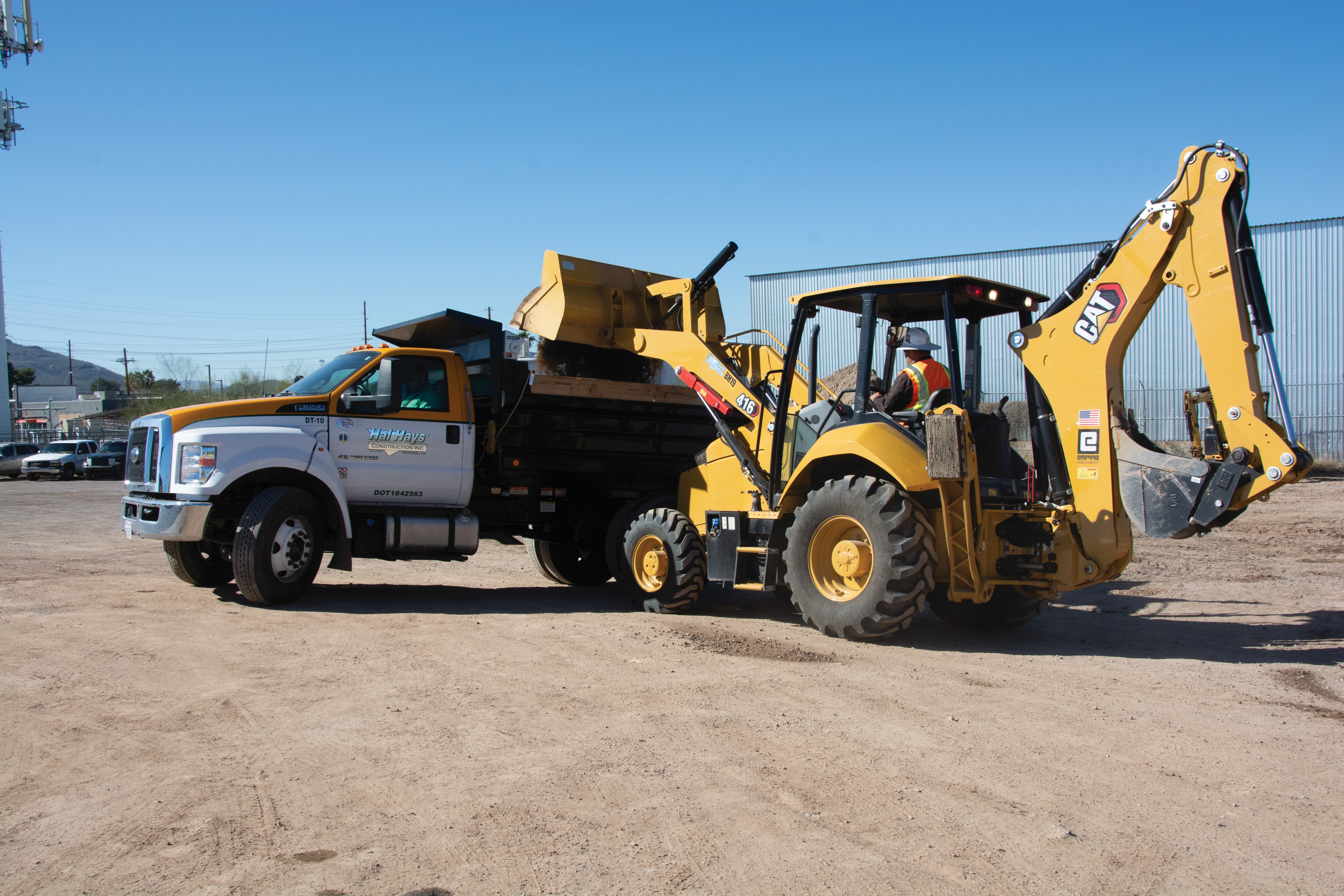 backhoe dumping debris in truck bed