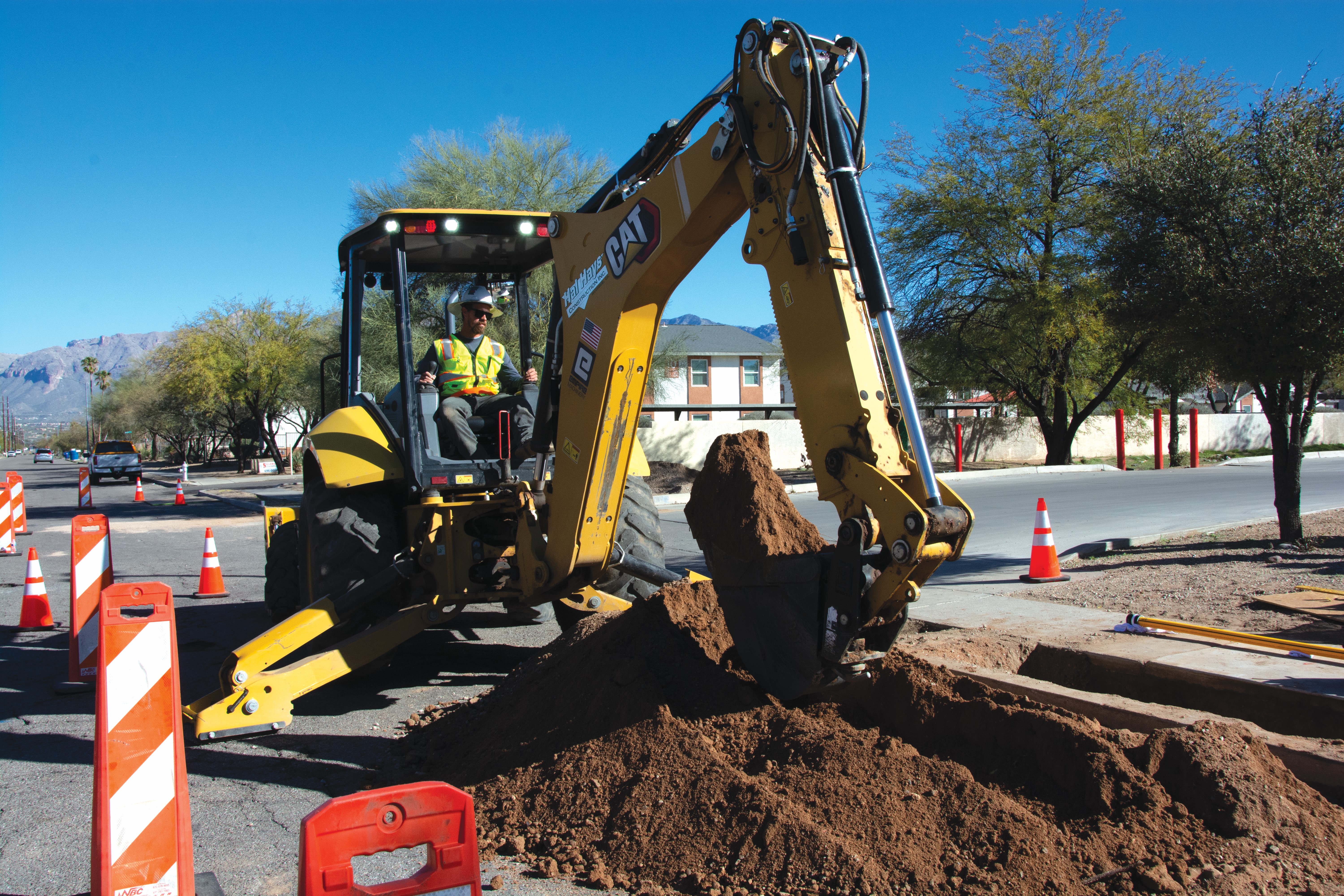 backhoe digging into the street ground with bucket