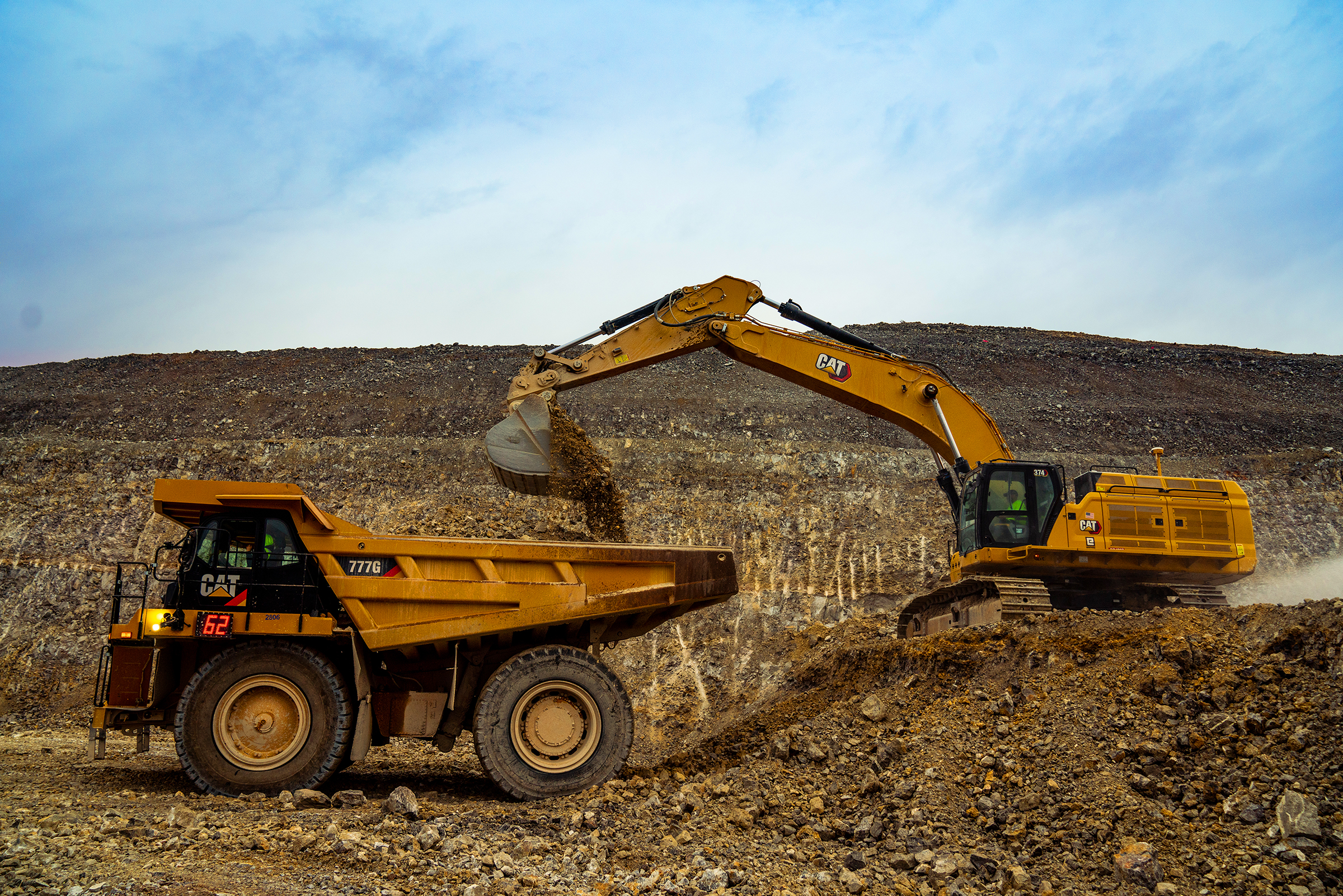 excavator dumping dirt into a off highway truck at a mining site